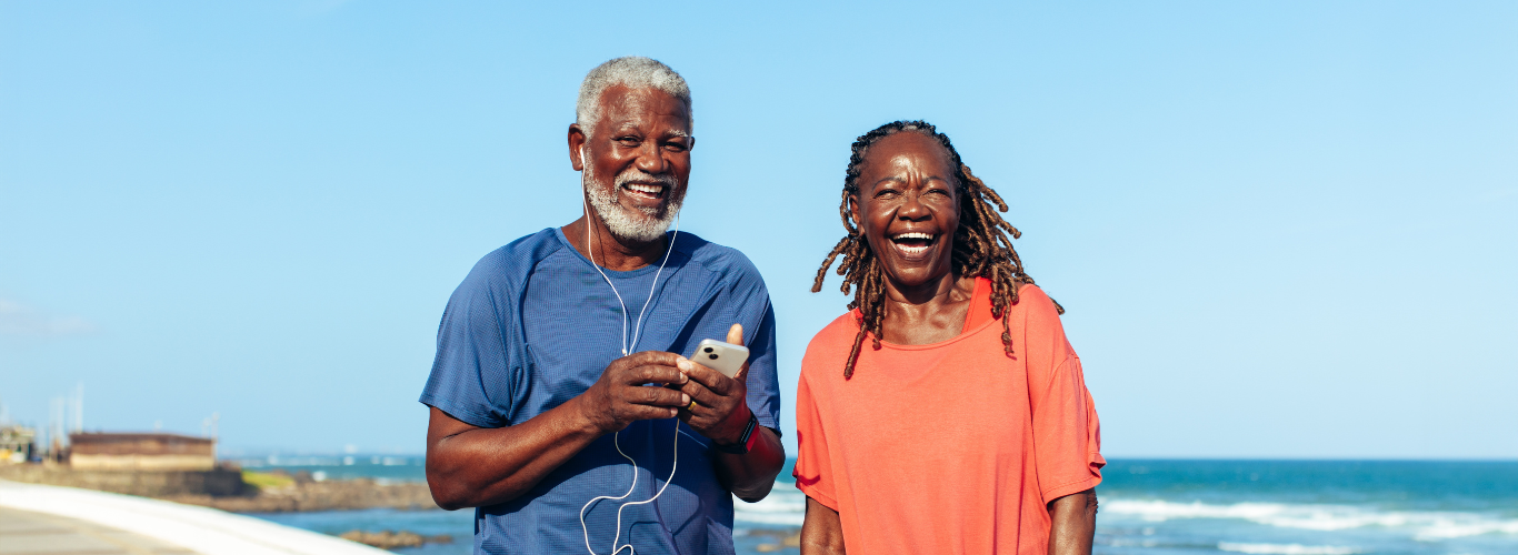 Older couple walking and smiling by the beach
